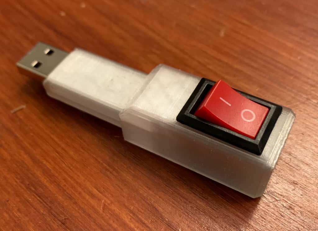 A picture of a thumbdrive in a 3D printed enclosure with an on/off switch on top.